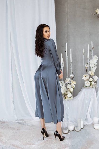 Woman in a gray dress standing in a decorated room with white flowers and candles.