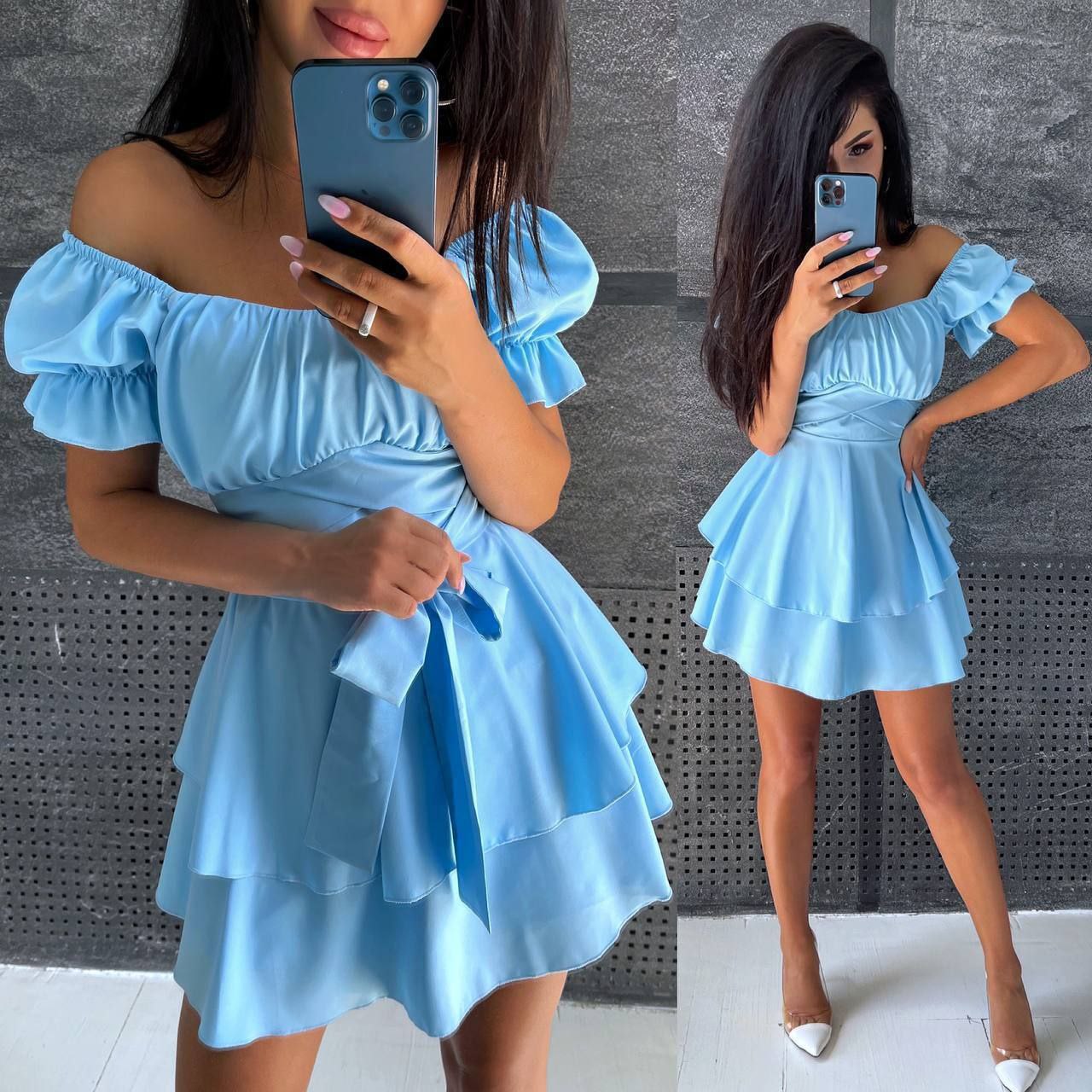 Woman wearing a light blue off-shoulder dress taking a mirror selfie.
