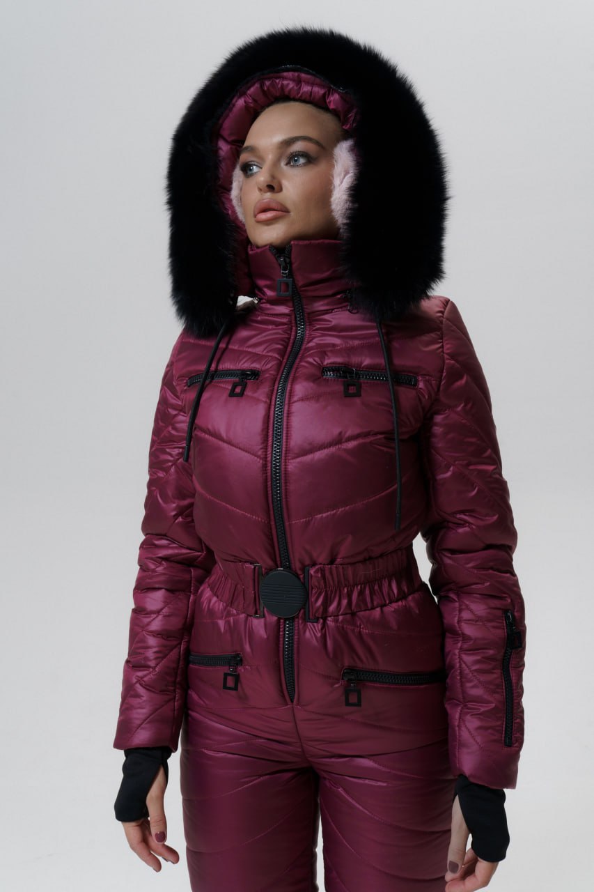 Person wearing a maroon puffer suit with a fur-lined hood on a white background
