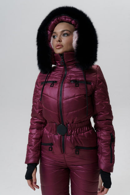 Person wearing a maroon puffer suit with a fur-lined hood on a white background
