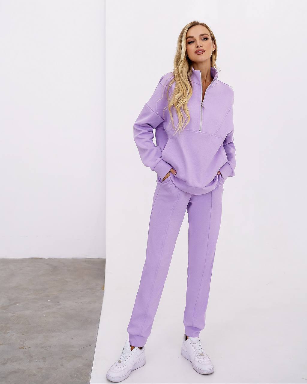 Woman wearing a lavender tracksuit against a white background