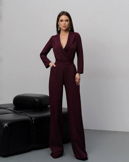 Woman wearing a burgundy jumpsuit against a gray background