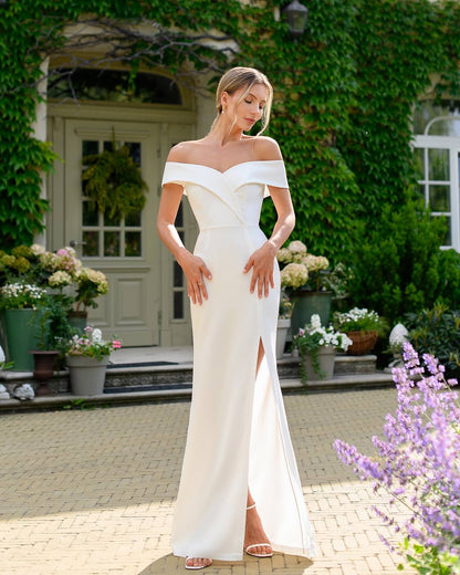 Woman in a white off-shoulder gown standing in a garden setting.