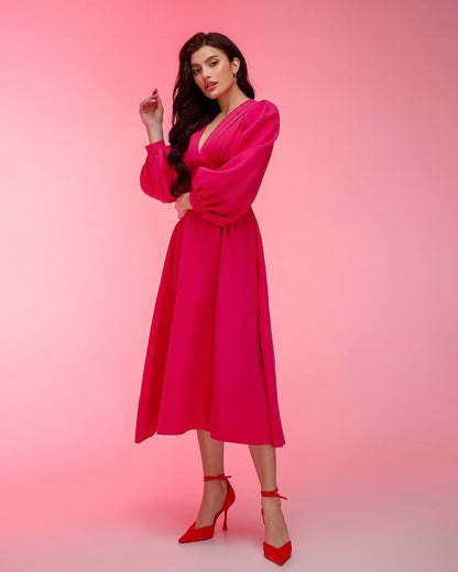 Woman wearing a bright pink dress with long sleeves against a pink background
