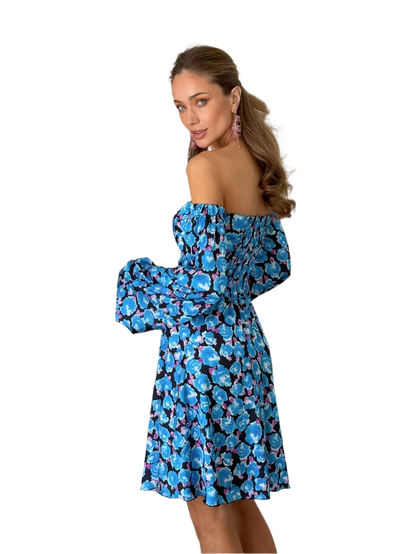 Woman wearing a blue floral off-shoulder dress on a white background