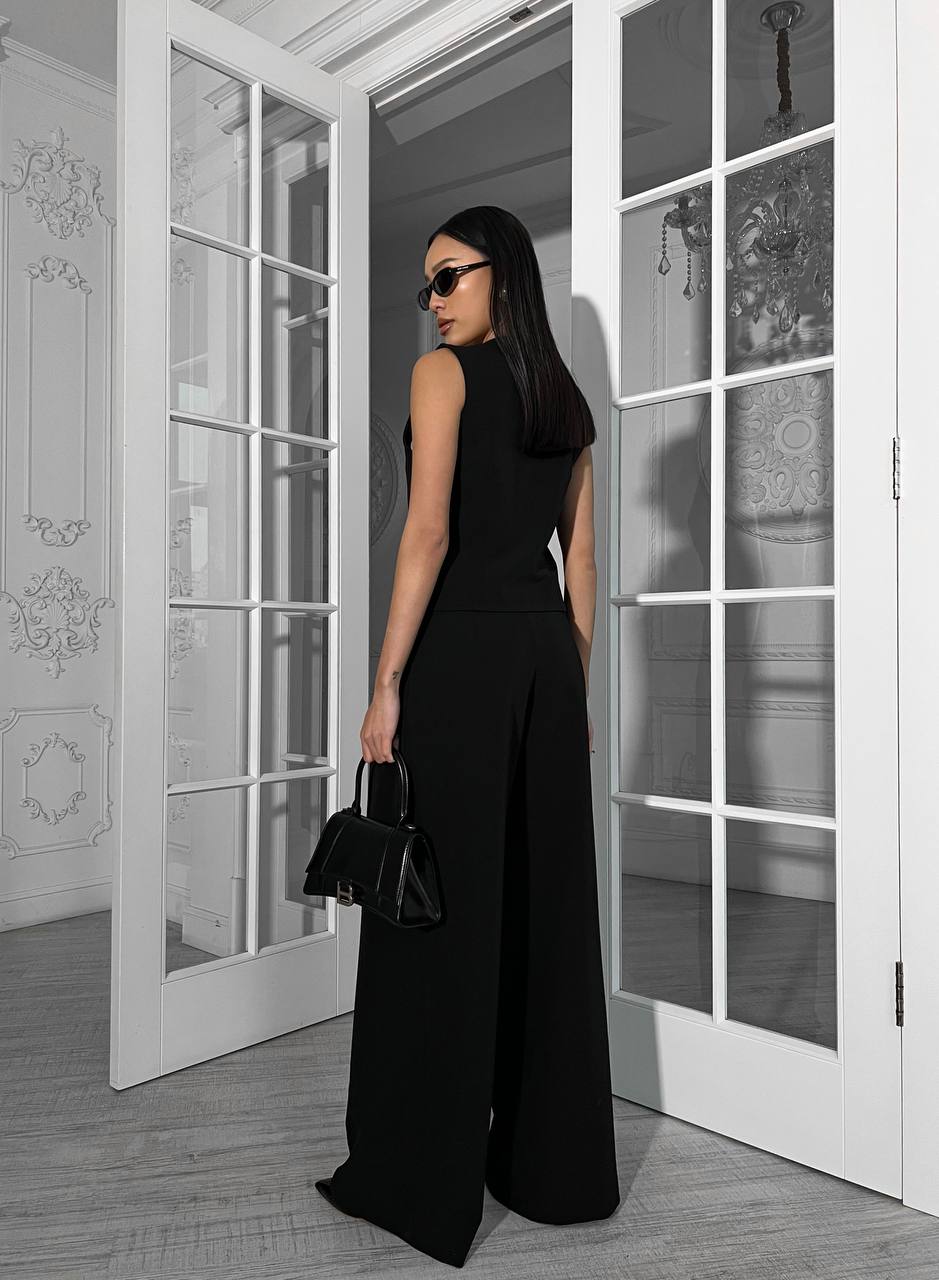 Woman in a black outfit standing in a room with white French doors.