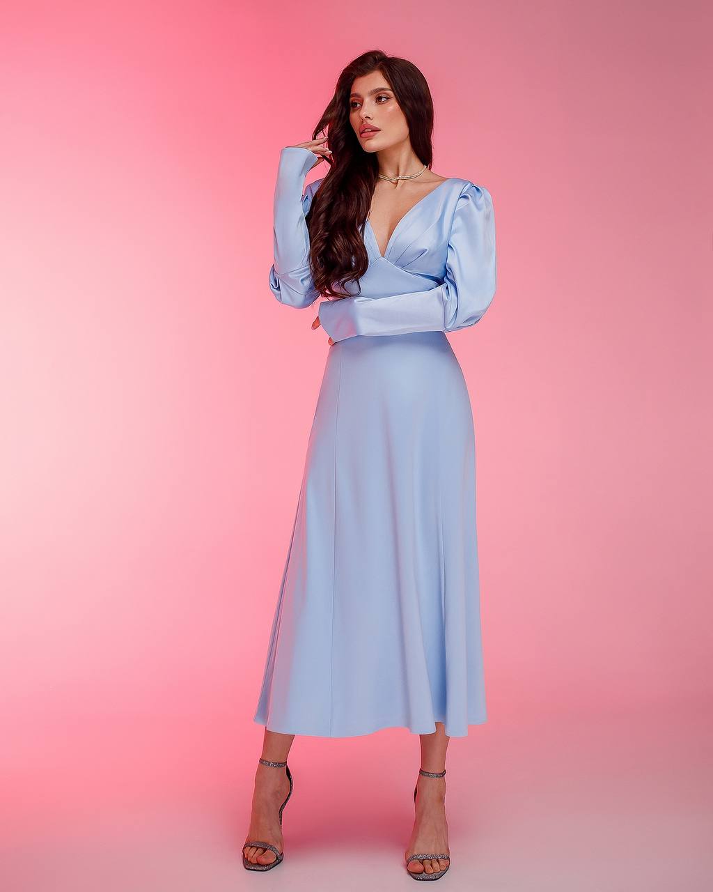 Woman wearing a light blue dress with a pink gradient background