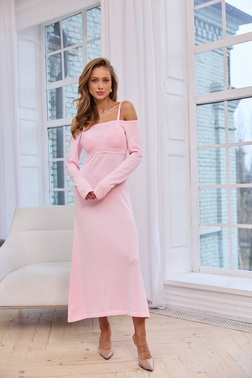 Woman in a pink dress standing in a room with large windows.
