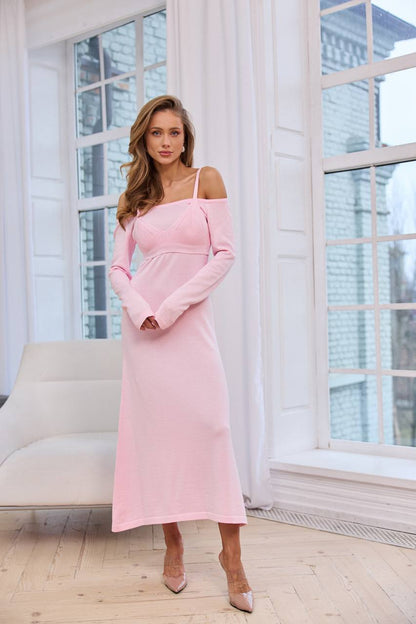 Woman in a pink dress standing in a room with large windows.
