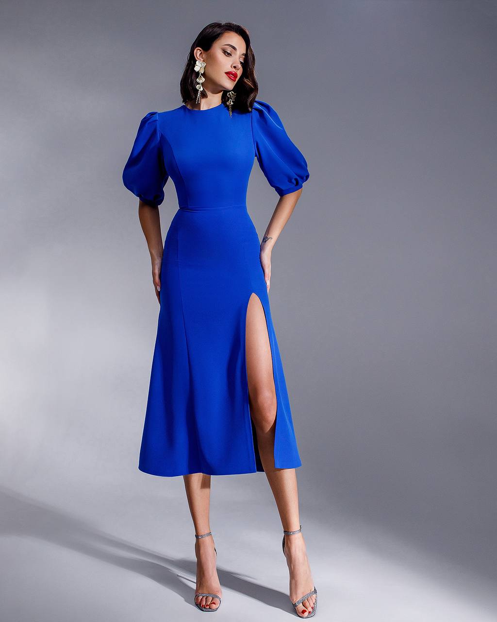 Woman wearing a blue dress with puff sleeves on a gray background