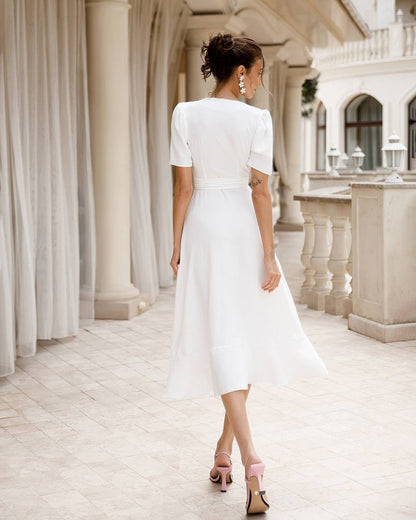 Woman in a white dress standing in an elegant interior setting