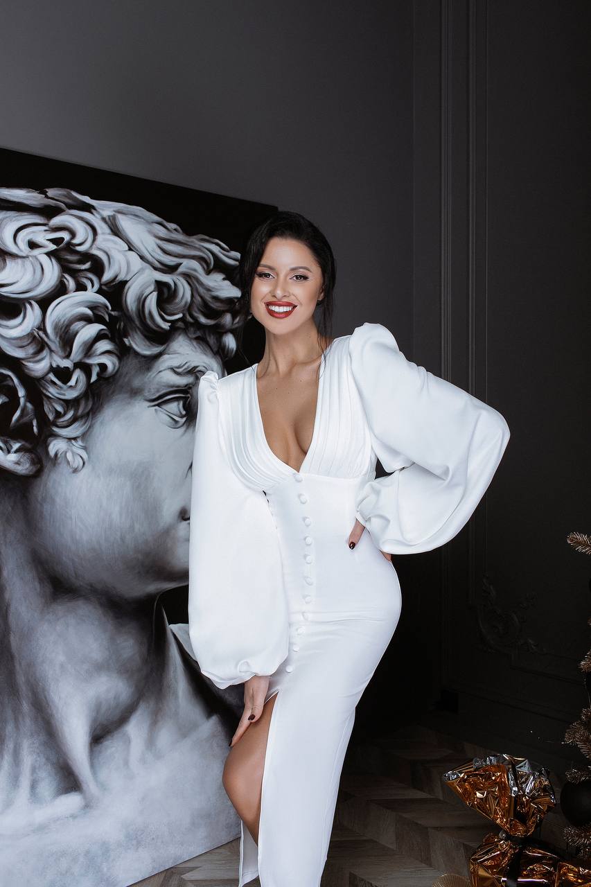 Woman in a white outfit posing in front of a black and white sculpture