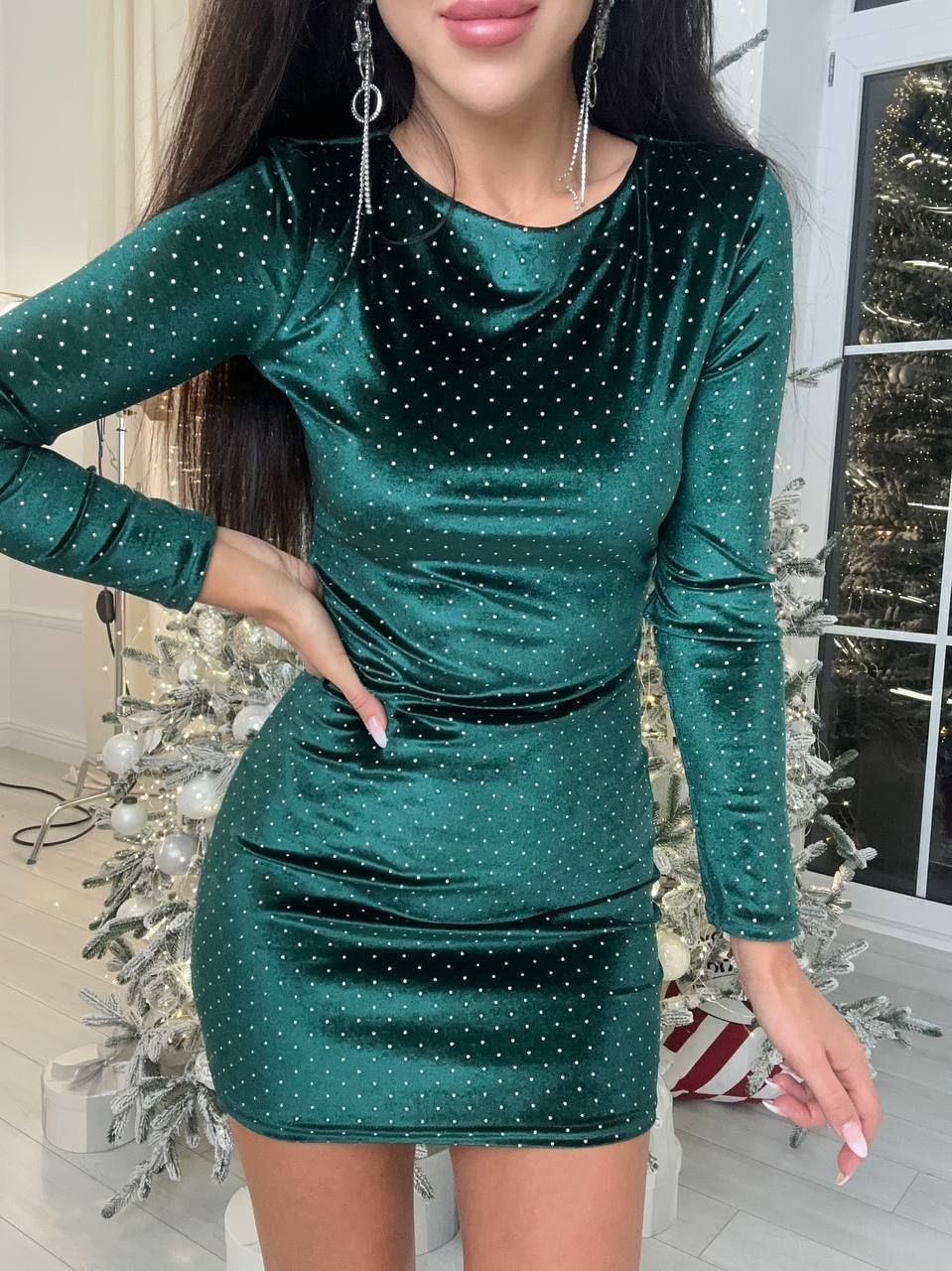 Woman wearing a green sequin dress with Christmas decorations in the background