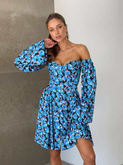Woman wearing a blue floral off-shoulder dress against a neutral background