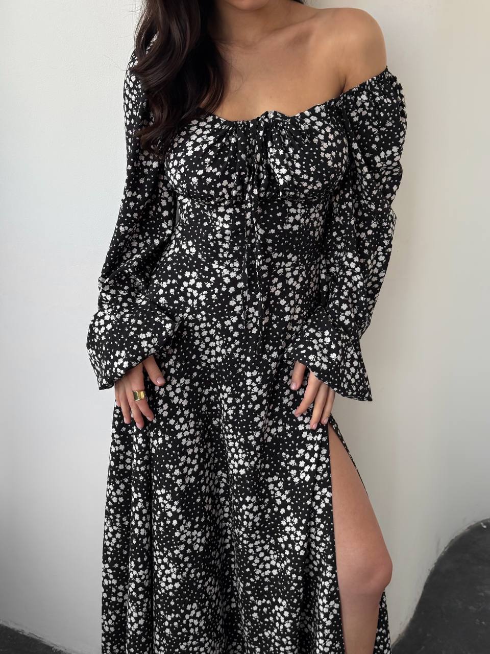 Black and white floral off-shoulder dress with long sleeves and a slit on a plain background