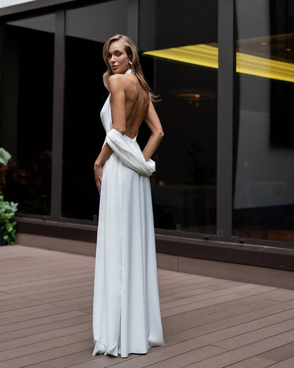 Woman in a white dress standing on a wooden deck with a modern building in the background