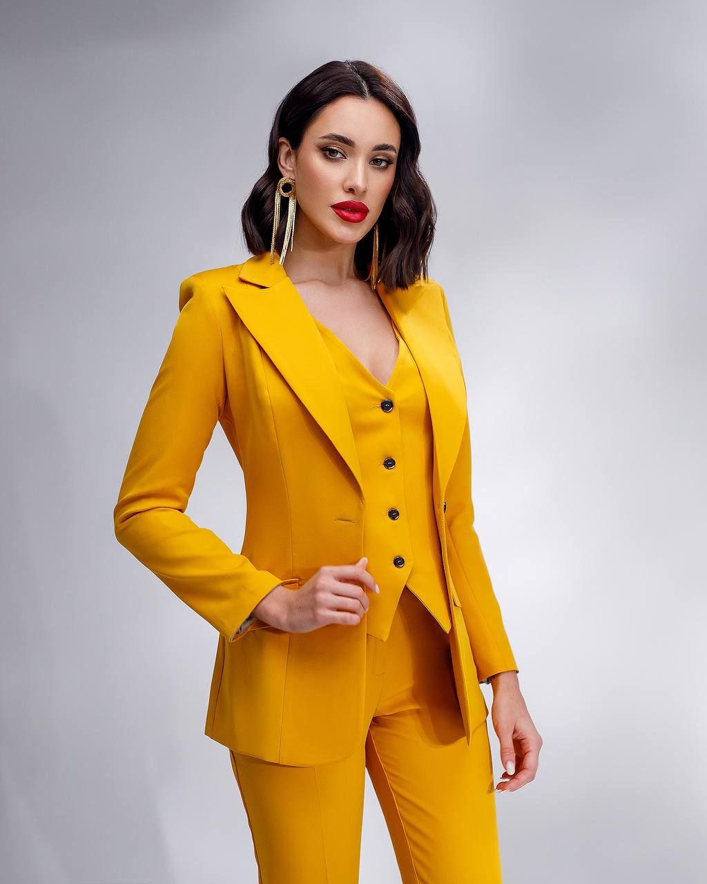 Woman wearing a yellow suit against a gray background