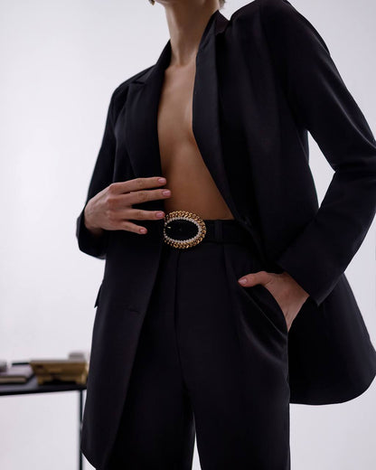 Person wearing a black outfit with a decorative belt against a white background
