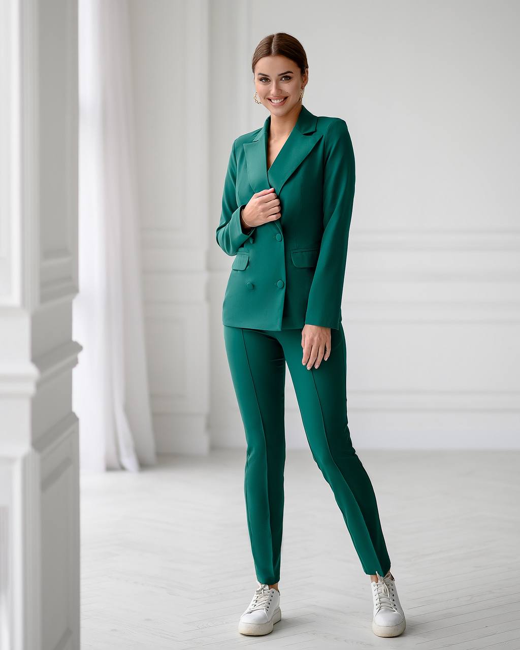 Woman wearing a green suit standing in a bright room with white walls.