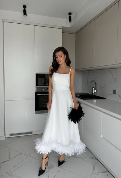 Woman in a white dress standing in a modern kitchen.