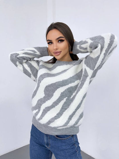 Woman wearing a gray and white zebra pattern sweater against a plain background