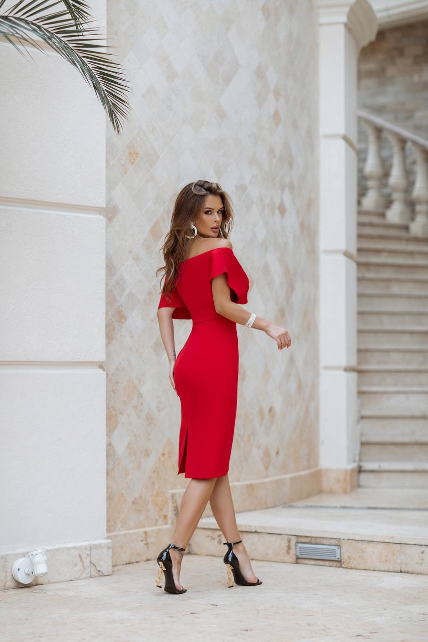 Woman in a red off-shoulder dress standing in front of a classical building.
