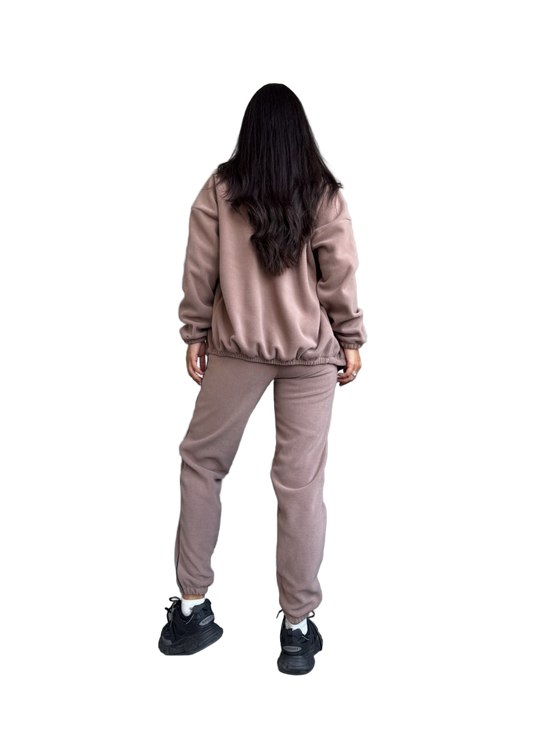 Person wearing a beige tracksuit on a white background