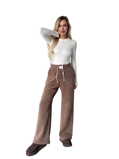 Woman wearing brown pants and a white top on a white background