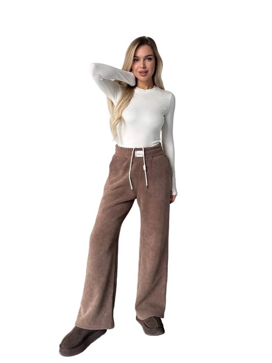 Woman wearing brown pants and a white top on a white background