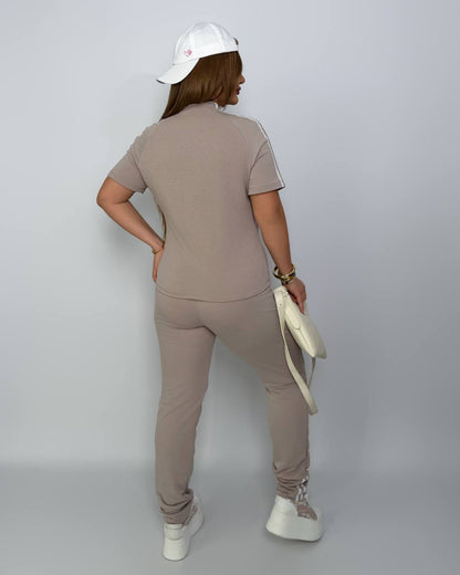 Person wearing a beige outfit with a white cap on a plain background