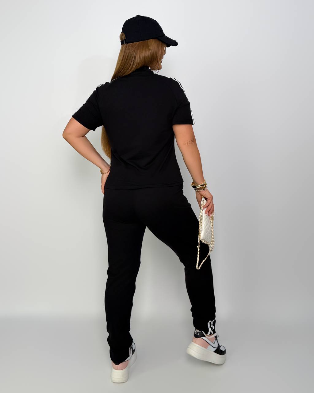 Person wearing a black outfit with a cap on a plain background