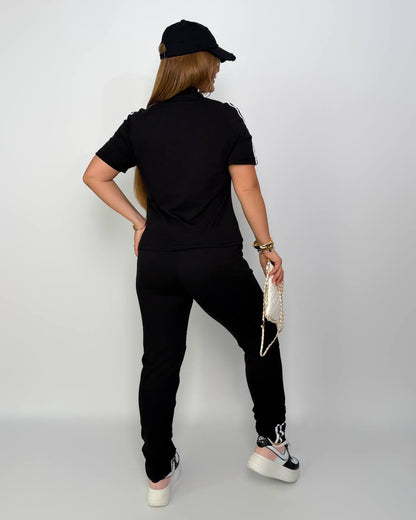 Person wearing a black outfit with a cap on a plain background