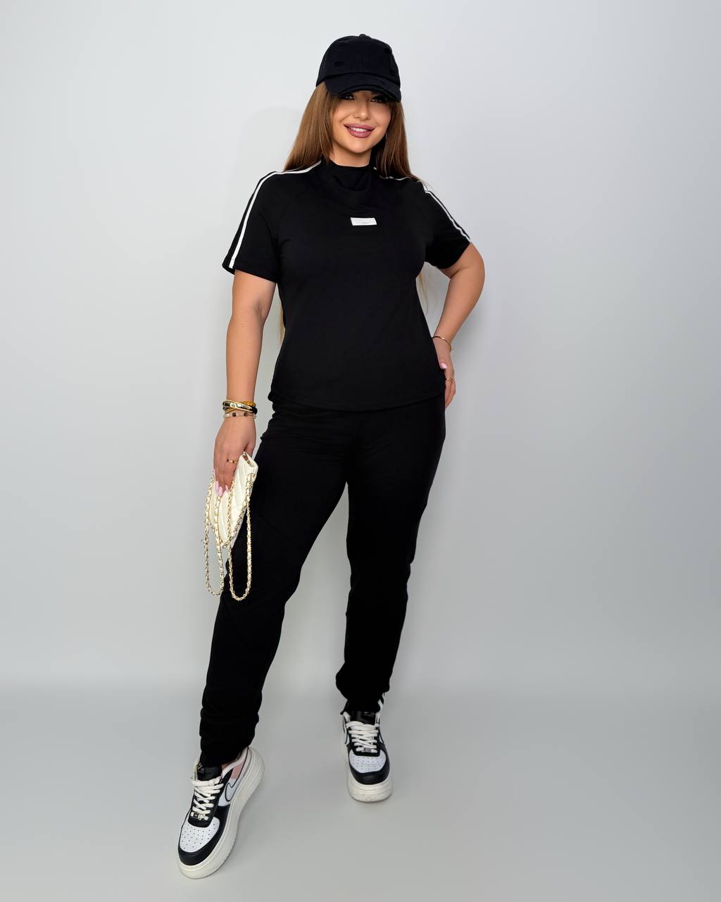 Person wearing a black outfit with white accents on a plain background