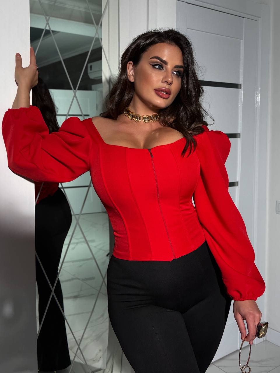 Woman wearing a red blouse with puffed sleeves indoors.
