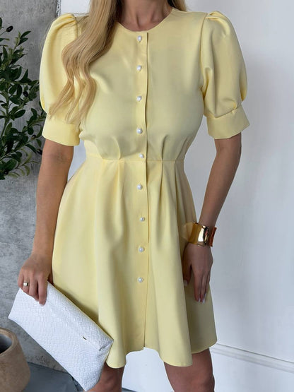 Woman wearing a yellow dress with puff sleeves against a neutral background