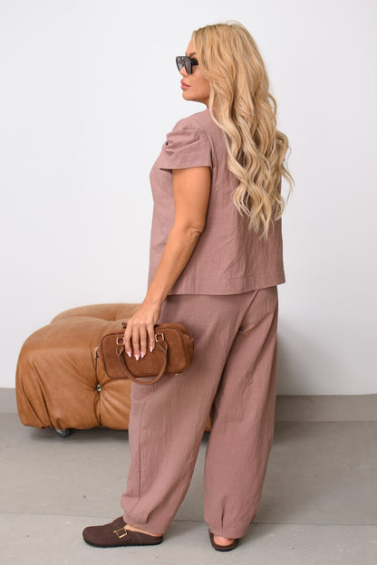 Woman in a brown outfit holding a brown bag against a white background