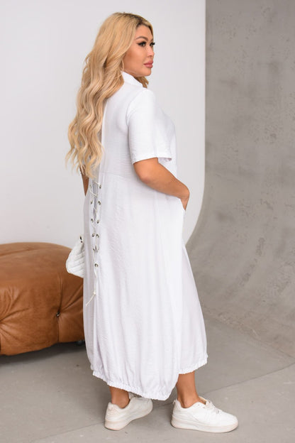 Woman wearing a long white dress with a plain background