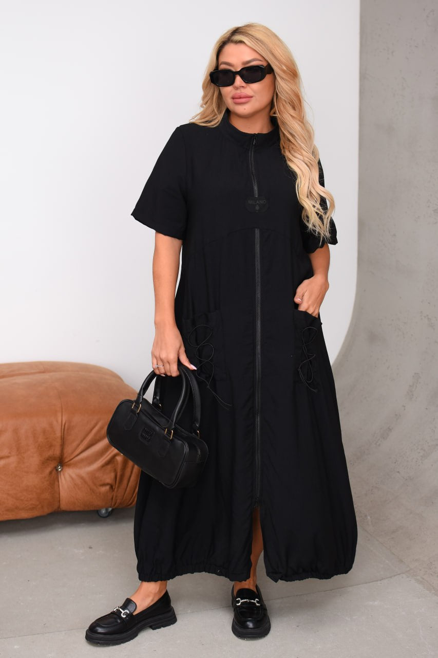 Woman wearing a black dress with sunglasses and holding a black handbag.