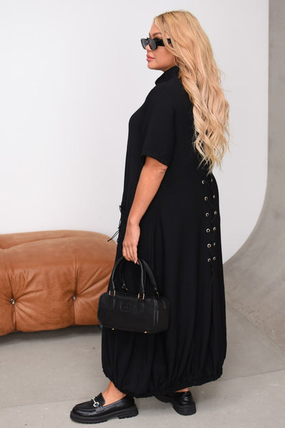 Woman wearing a long black dress with a brown sofa in the background