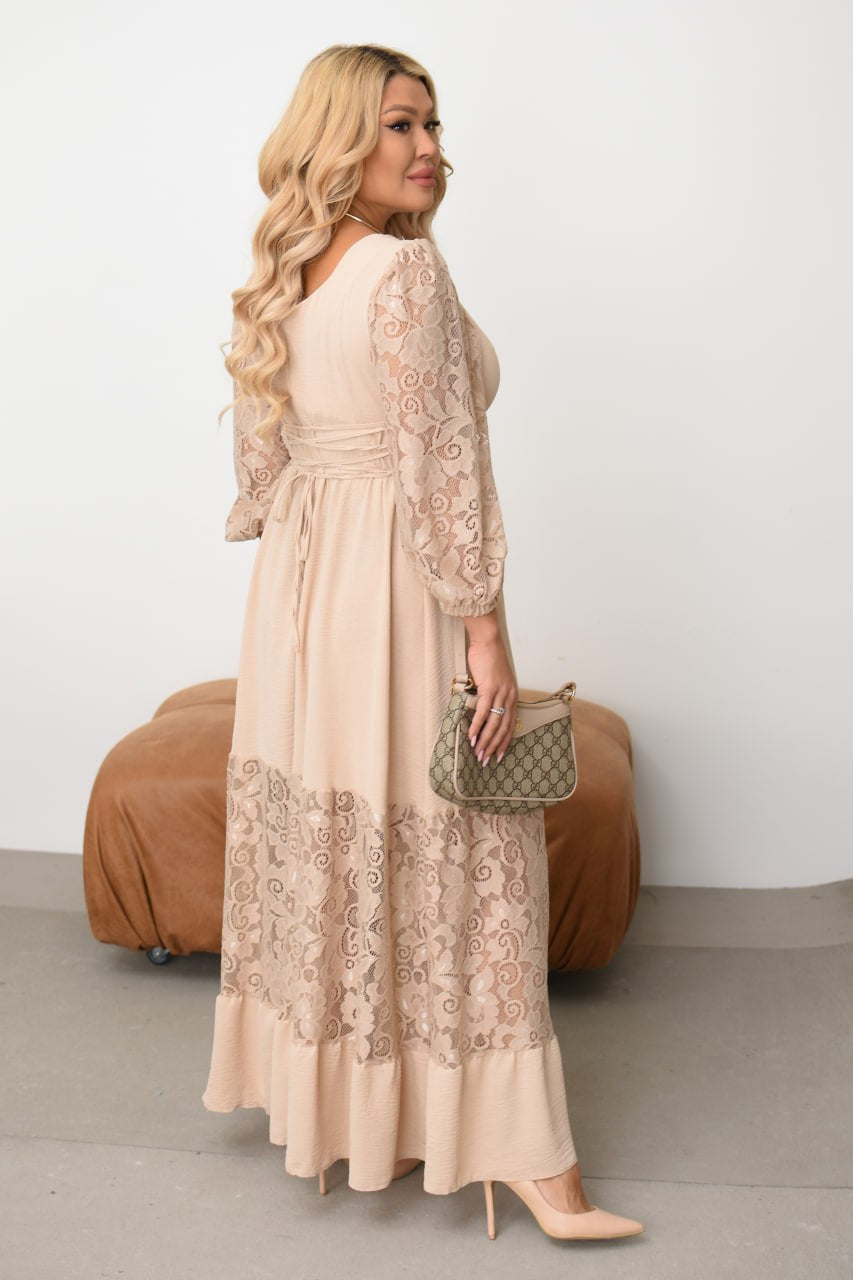 Woman wearing a beige lace dress holding a green handbag against a white background