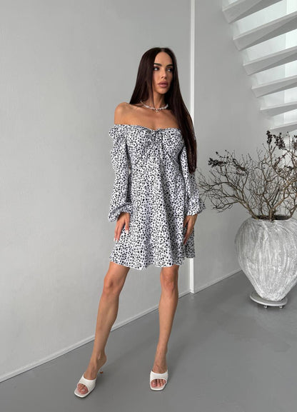 Woman wearing a patterned off-shoulder dress in an indoor setting.