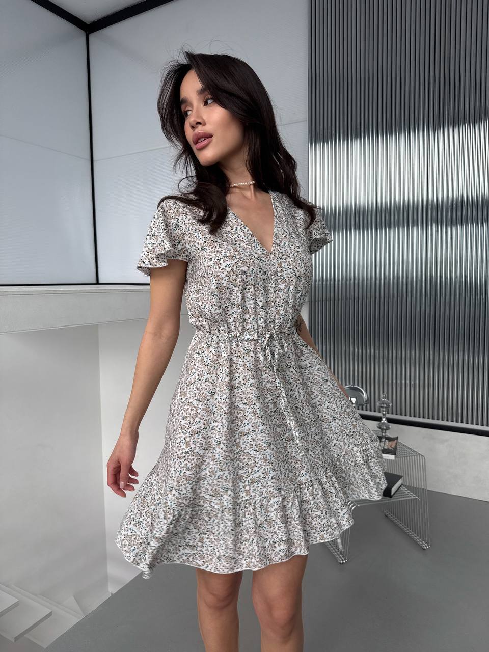 Woman wearing a floral dress in a modern indoor setting