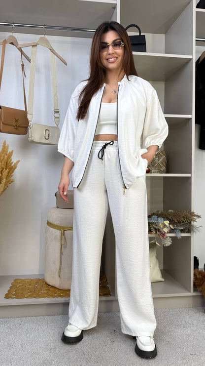 Woman in a white outfit standing in a room with shelves and decor.