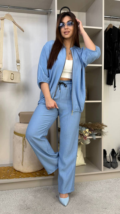 Woman in a blue outfit posing in a room with shelves and decor.