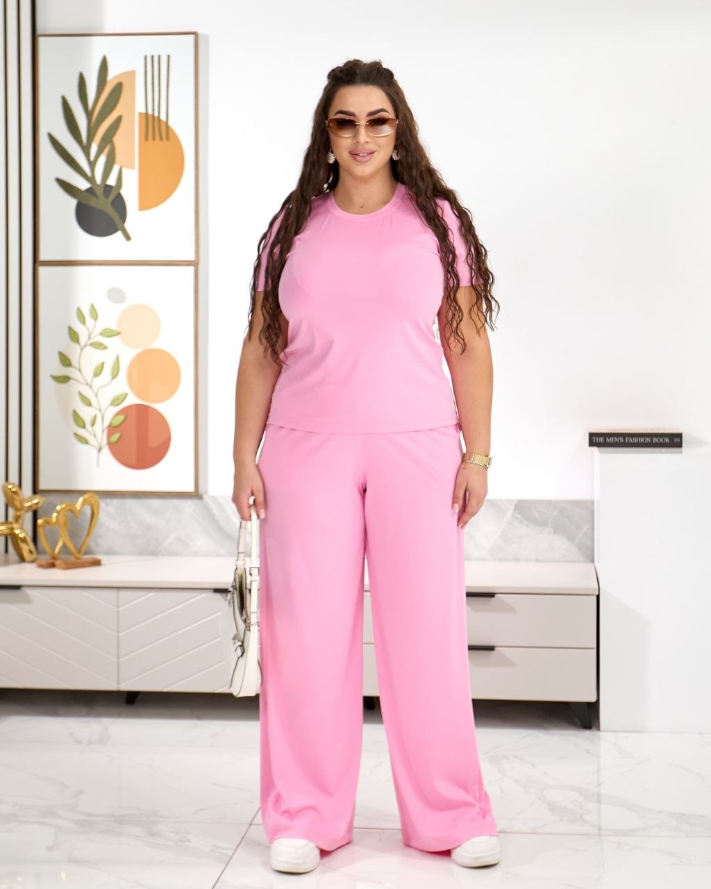 Woman in a pink outfit standing in a room with decorative elements.