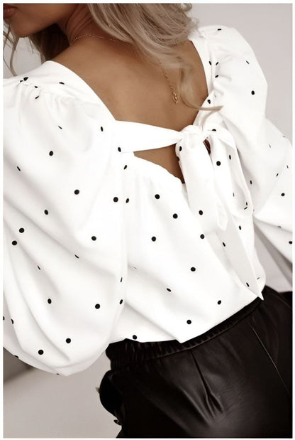 White blouse with black polka dots and a large bow at the back, worn by a person.