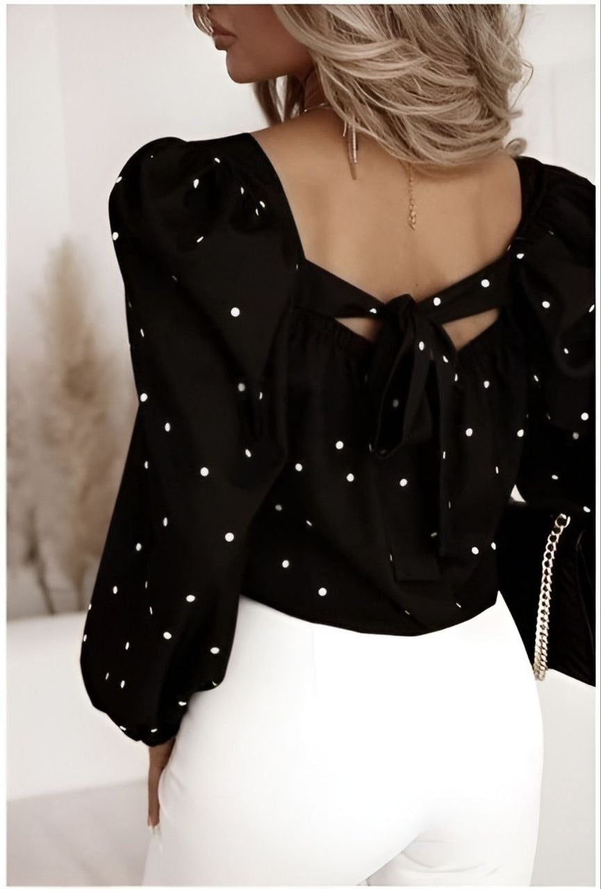 Black blouse with white polka dots and cut-out design on a neutral background