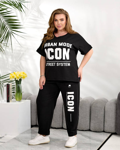 Woman wearing a black 'ICON' t-shirt and pants in a living room setting.