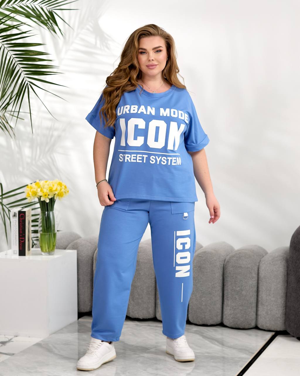 Woman wearing a blue 'ICON' outfit in a modern living room setting