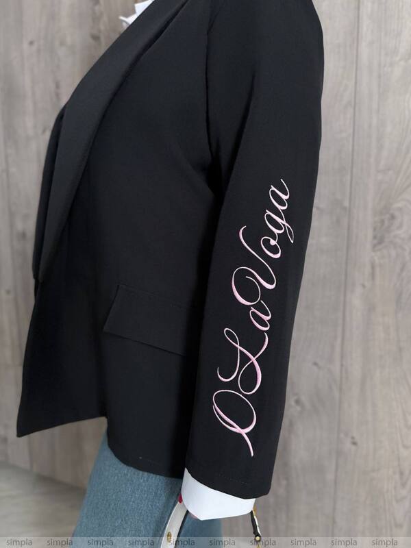 Black blazer with 'La Vaga' branding on a wooden background